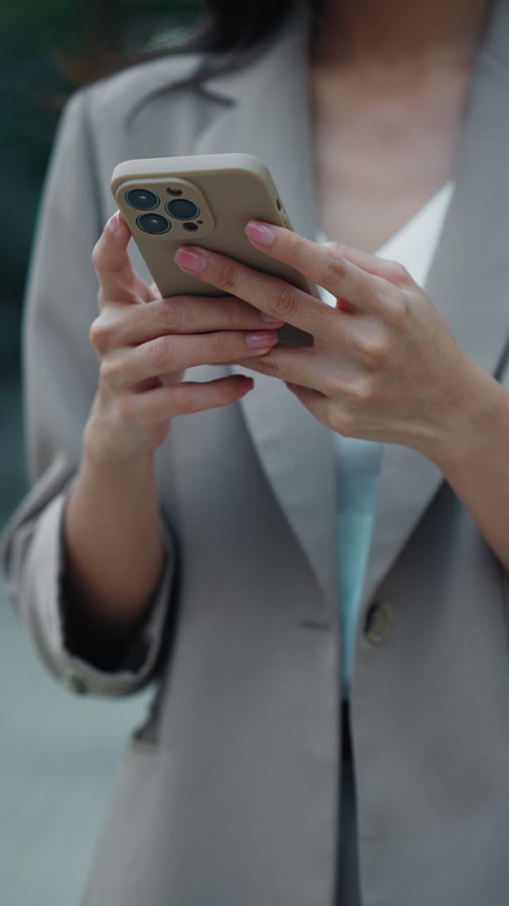 Woman using a smartphone in a light beige blazer