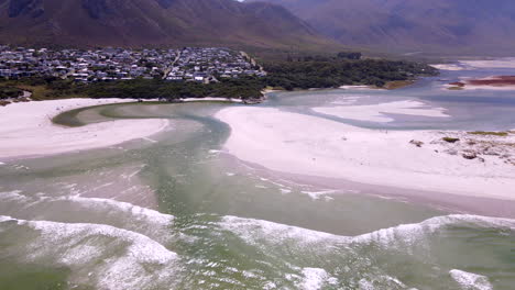 Aerial-tilt-up-over-Klein-River-estuary-mouth-as-it-breaches-beach-into-ocean