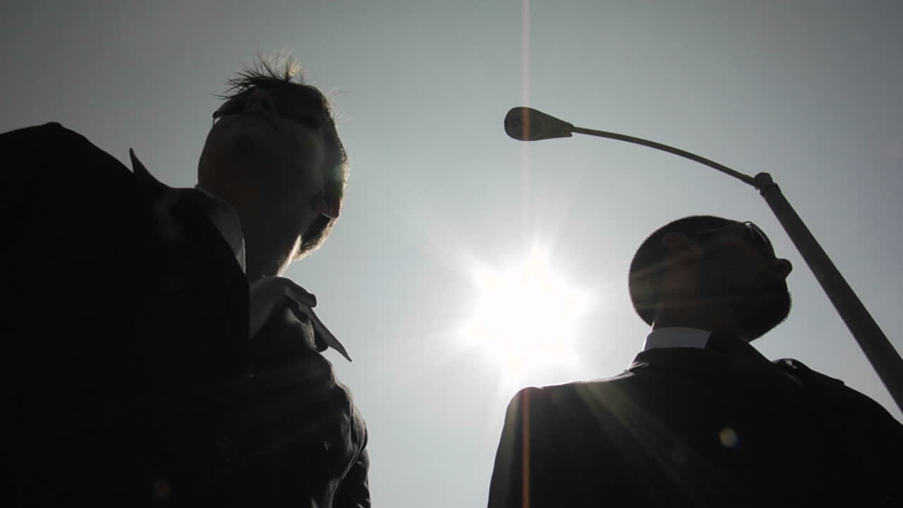 실루엣을 한 남자가 다른 실루엣을 한 남자에게 봉투를 교활하게 건네다