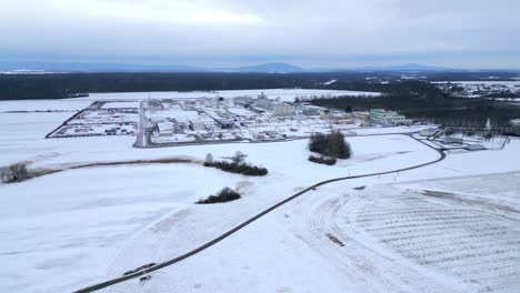 aerial tilt-up reveal of gas compressor station covered in snow during winter