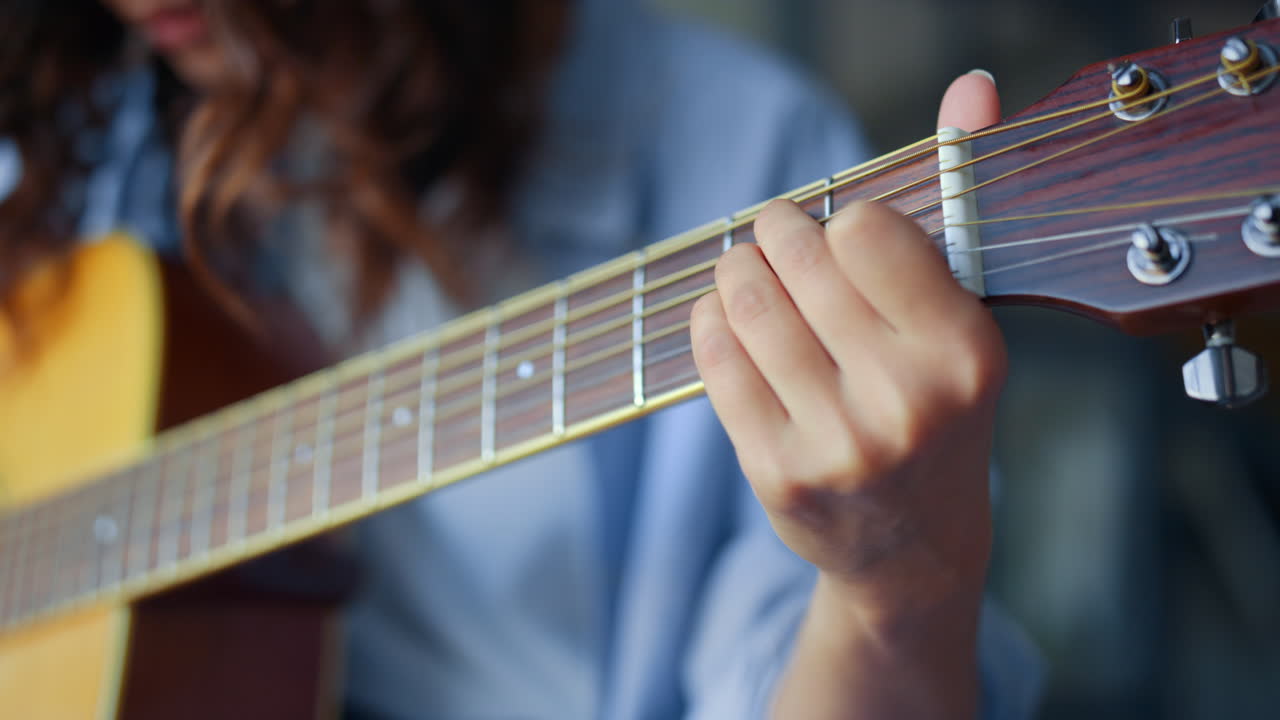 mano de mujer tocando acordes en la guitarra. dedos de niña tocando cuerdas en la guitarra