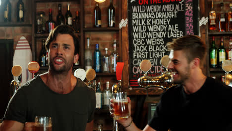 excited friends watching television while having beer