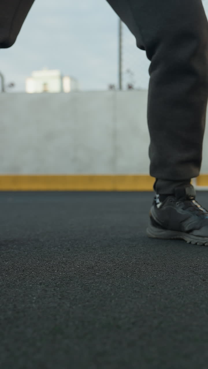 vista de ángulo inferior de un atleta en posición de cuclillas con las manos juntas, realizando un entrenamiento intenso en un campo deportivo al aire libre, mientras la pelota de fútbol rueda cerca