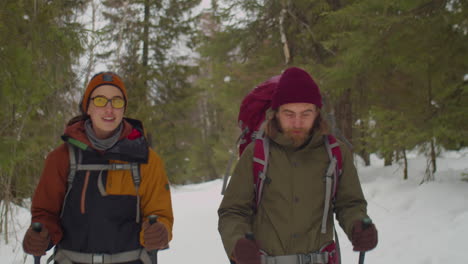 cheerful couple hiking in winter forest