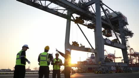 construction workers collaborate on a project at a shipping port during sunset, emphasizing teamwork and safety protocols on site.