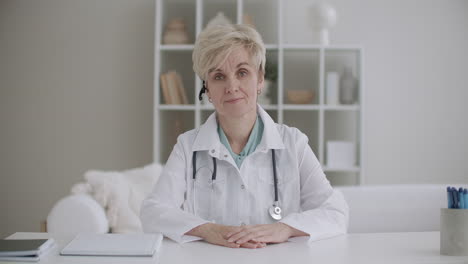 online consultation with doctor aged woman dresses medical gown listening and nodding looking at camera