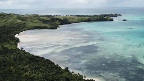 drone flying over private green fijian island beach