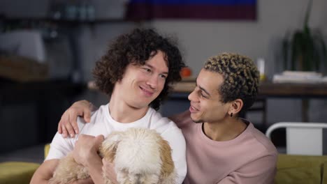 Lovely-homosexual-male-gay-couple-in-love-enjoying-time-together-while-stroking-the-dog-on-sofa