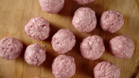 las albóndigas crudas en la tabla de cortar de madera giran lentamente.