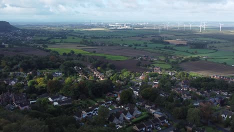 campo de tierras de cultivo de cheshire turbinas de parques eólicos que generan energía verde renovable vista aérea izquierda órbita ancha