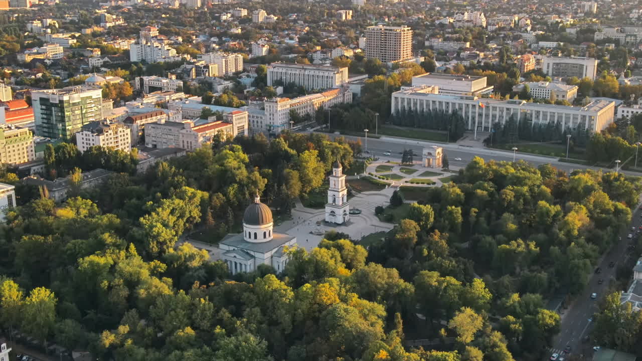 Aerial drone view of Chisinau downtown at sunset. Panorama view of central park, Cathedral, bell tower, a lot of greenery, walking people, buildings, Goverment. Moldova