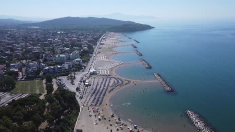 Luxury-beach-with-many-beds-and-umbrellas-on-Italy-coastline,-aerial-orbit-view