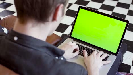 person working on a laptop with a green screen