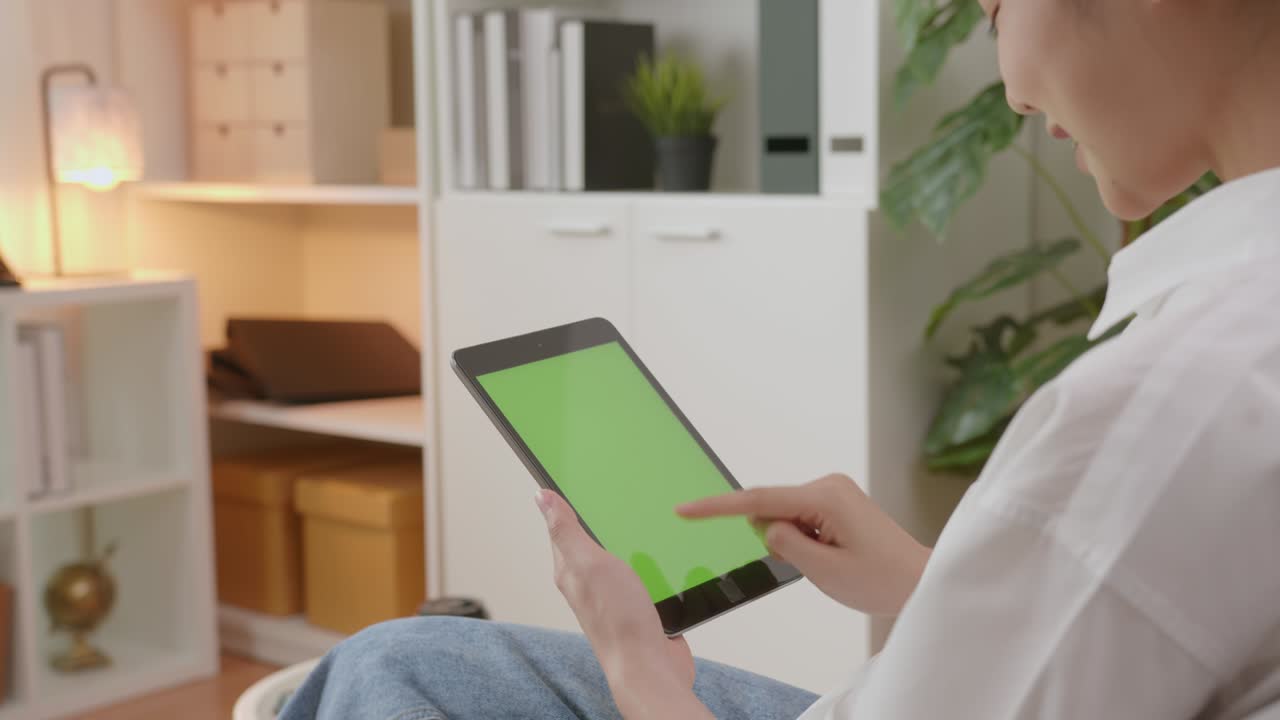 mujer sosteniendo una tableta digital con pantalla verde y dispositivo táctil navegando por internet.