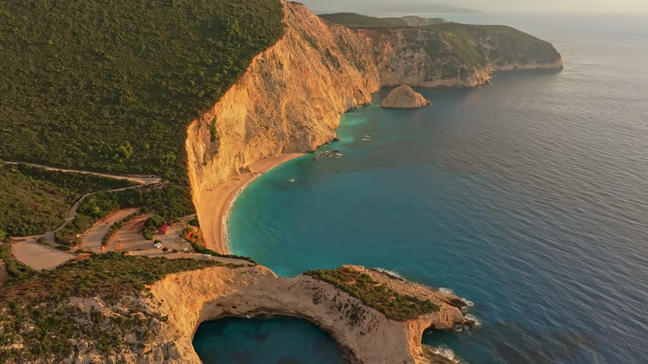 I colori del tramonto si diffondono su mare e costa sassosa, Lefkada, Grecia