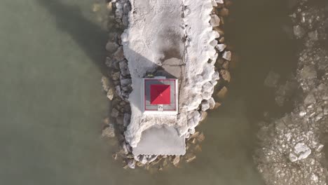 A-snowy-Southampton-pier-with-lighthouse-jutting-into-calm-waters-at-golden-hour,-aerial-view