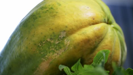 Extreme-closeup-of-Ripe-yellow-papaya-paw-paw-spinning-on-a-rotating-platform-displaying-it's-beautiful-and-unique-spots-and-skin