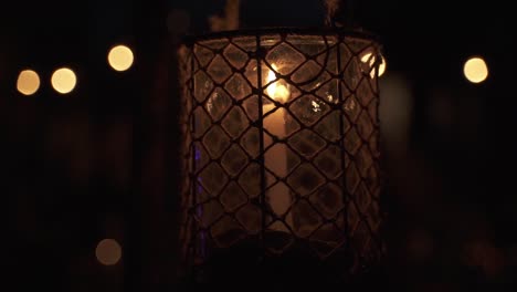 a candle in metal and glass lantern with beautiful bokeh