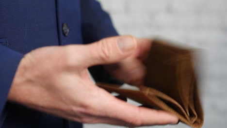 close up of an empty wallet being opened by a business man showing that he has no money