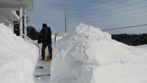 Hombre-Haciendo-El-Baile-Del-Hilo-Dental-Después-De-Terminar-De-Palear-La-Pasarela-Frente-A-La-Casa-Cubierta-De-Nieve