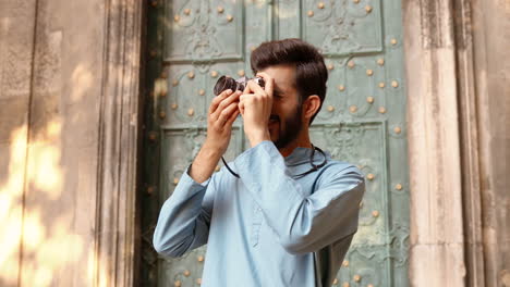 portrait of a handsome indian man taking pictures with a camera