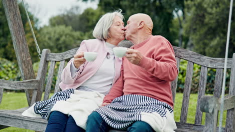 senior couple on swing in garden with kiss