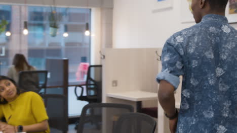 Man Walking Into An Office And Sitting Down With Colleagues