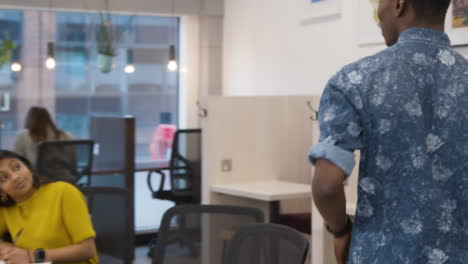 man walking into an office and sitting down with colleagues