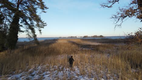 Male-photographer-hikes-towards-lake-with-snow-in-winter-time