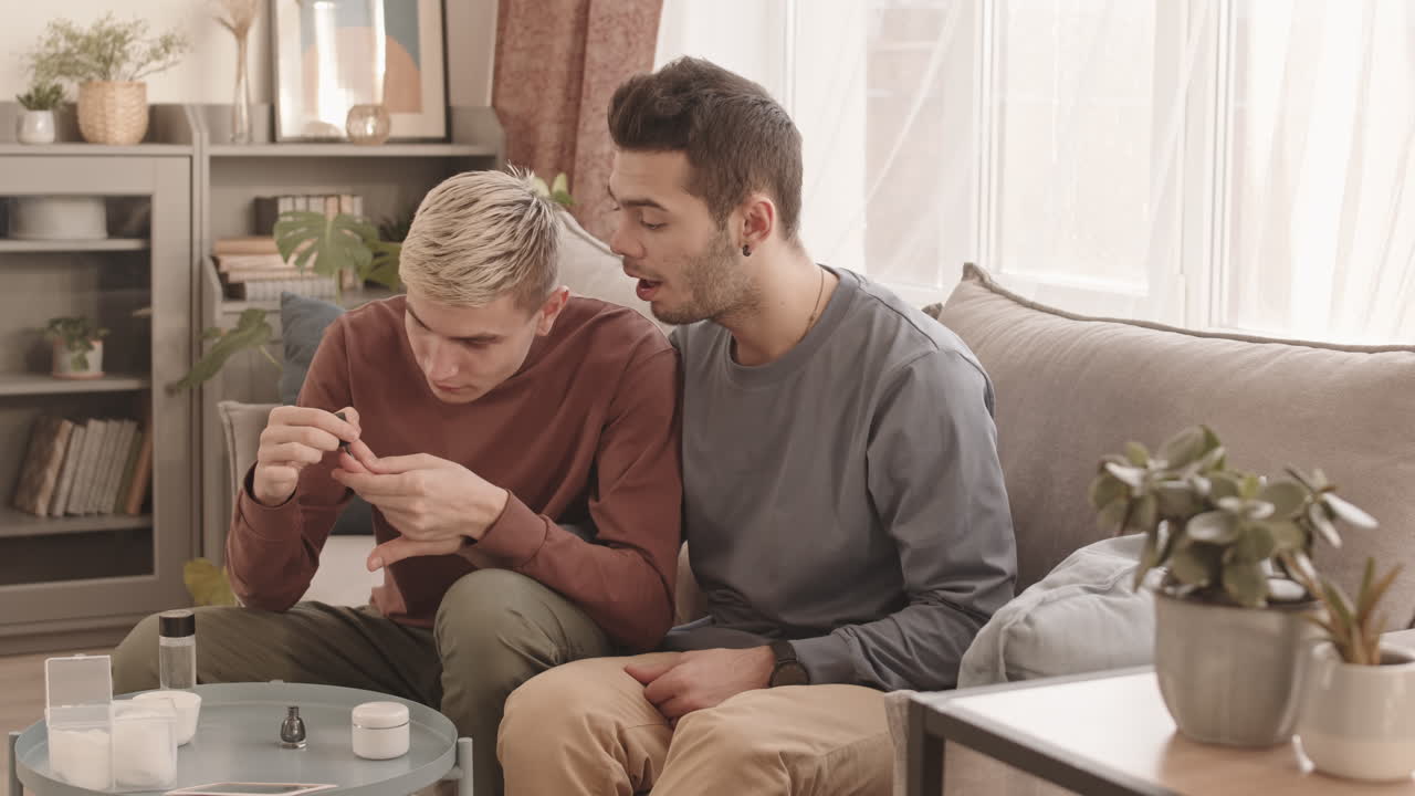 Blond-haired Man Applying Nail Polish on Boyfriend Fingernails