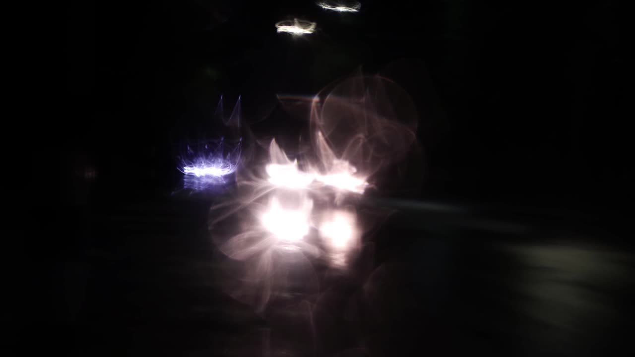 몇 개의 빨간색과 색의 빛 반점이 은 유리 위에 반사됩니다.