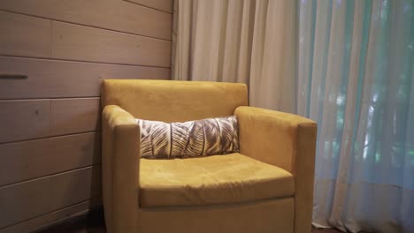 a slow panning shot showcases a bright yellow lounge chair in a luxury hotel room, adding a stylish and cozy touch to the modern decor