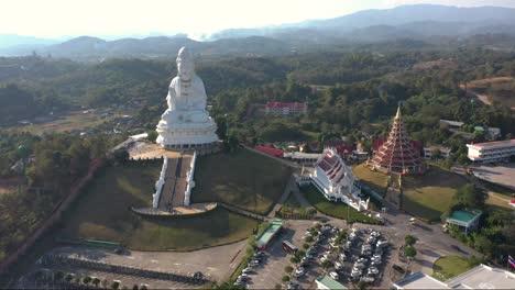 aerial drone of wat huay pla kang giant white big statue and pagoda temple with mountains and landspace in chiang rai, thailand