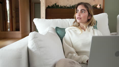 christmas time, relaxing on couch, woman smiling and looking away with laptop at home, copy space
