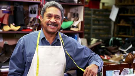 smiling shoemaker leaning in workshop