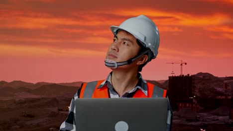 primer plano de ingeniero masculino asiático con casco de seguridad trabajando en una computadora portátil y mirando a su alrededor mientras está de pie en el sitio de construcción, maquinaria de minería