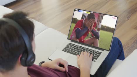 Video-Einer-Person,-Die-Auf-Der-Couch-Sitzt-Und-Sich-Ein-Fußballspiel-Auf-Dem-Laptop-Ansieht