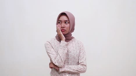 sad young asian muslim woman standing while thinking something