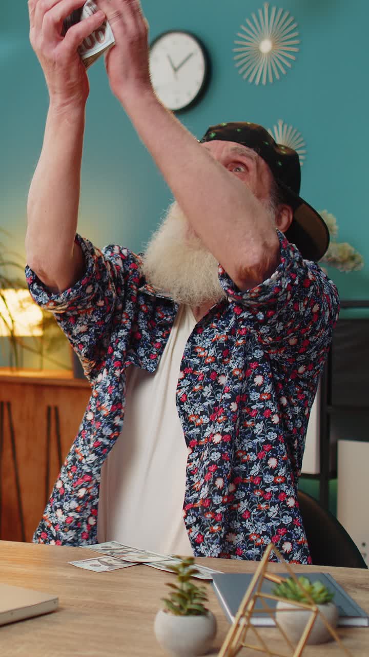 Money cash dollar falling on elderly man with laptop celebrating success winning goal achievement