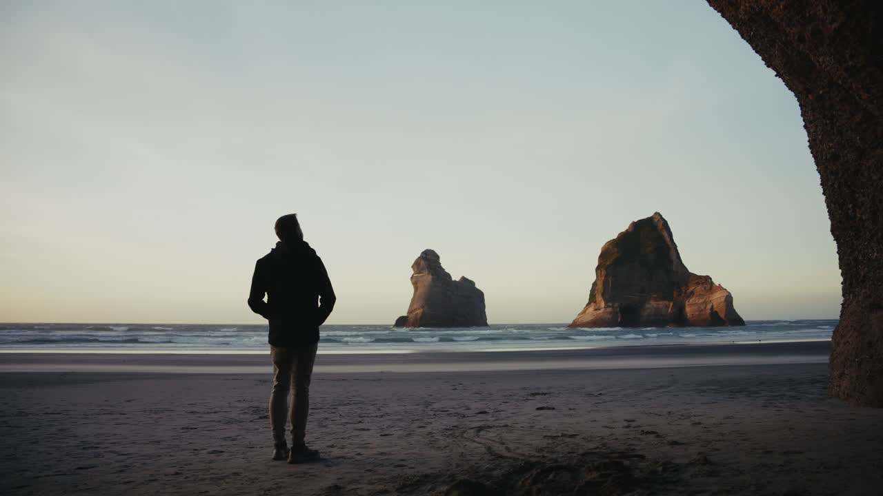 Man Contemplating the Coastline at Sunrise