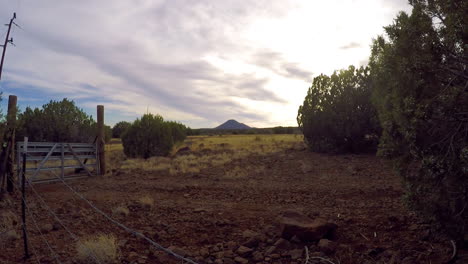 un lapso de tiempo disparado a lo largo de una cerca de alambre de púas y una puerta en el desierto de arizona