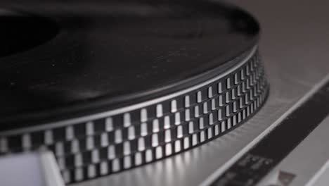 slow motion edge shot of black vinyl record spinning on antique turntable that comes to a stop