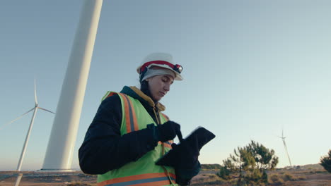female engineer walking at wind farm and using tablet