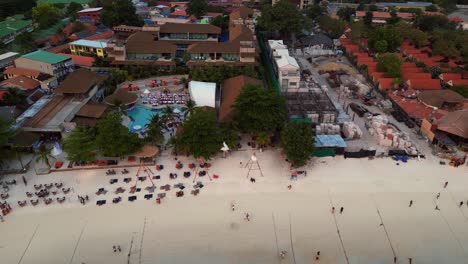 sun setting over a stunning thai beach, tourists soaking in the view