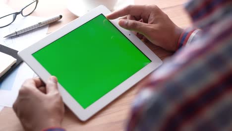 young man working on digital tablet with green screen