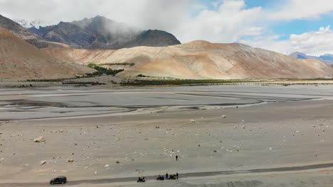 a small road crossing thought a big empty desert area with majestic mountains and cloudy sky in shyok, ladakh, india