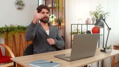Indian man gets email confirmation of partnership on laptop surprised smiles thumbs up big approval