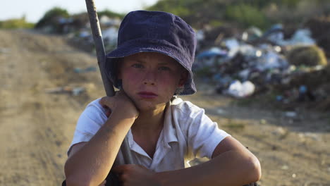 a sad boy in poverty near a garbage dump