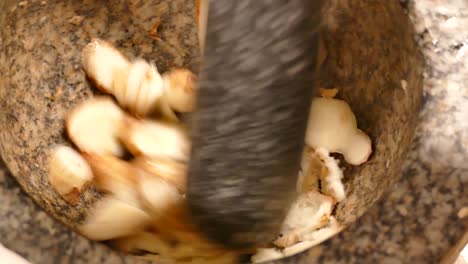 Crushing-Fresh-Galangal-in-Stone-Mortar,-Close-Up