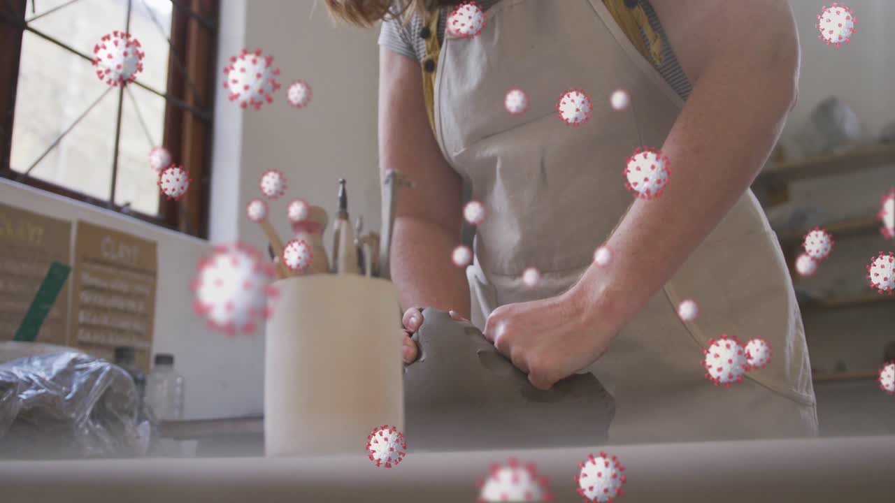 Potter inspecting clay, kneading to prep pottery with tools, window and virus drifting over hands
